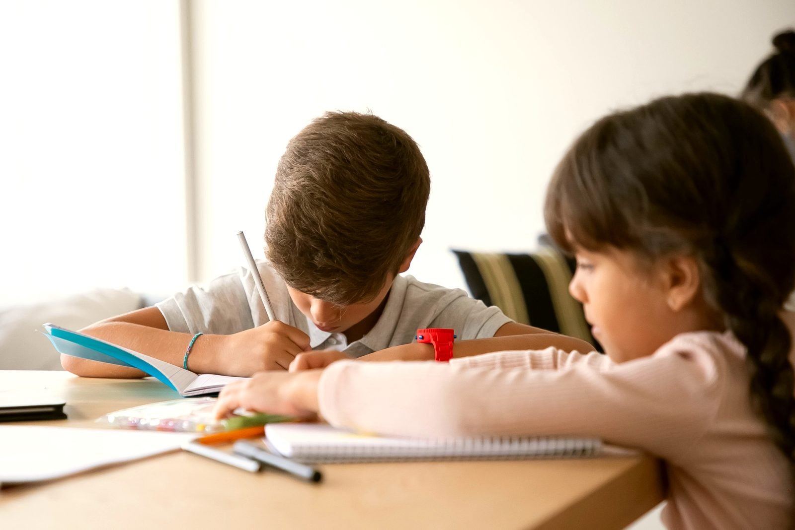 Younger school-age students writing in notebooks during a study session.